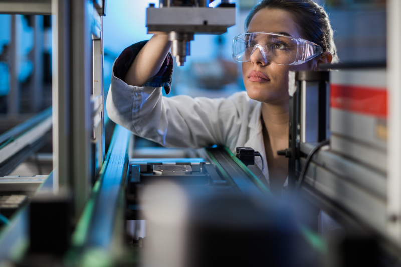 Female engineer examining machine part on a production line.